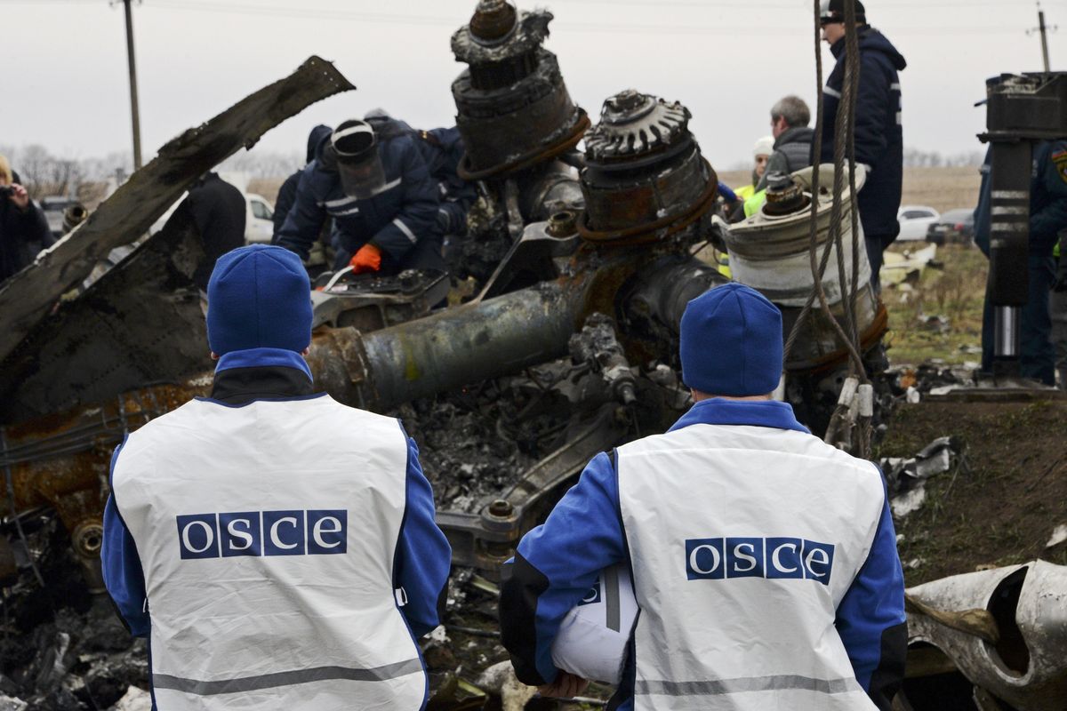 OSCE members watch as recovery workers in rebel-controlled eastern Ukraine load debris from the crash site of Malaysia Airlines Flight 17 on Sunday. (Associated Press)