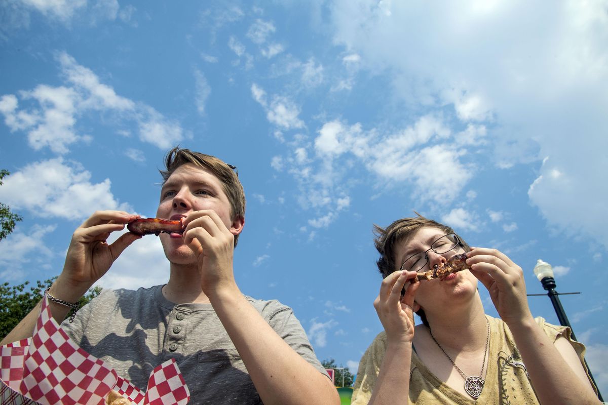 Edain Teague, 23, and Emily Bunting, 26, munch down on pork ribs during the opening day of the 38th annual Pig Out in the Park, July 30, 2017, in Riverfront Park in Spokane, Wash. The event runs through Monday, Sept. 4. (Dan Pelle / The Spokesman-Review)