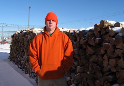 John Fojt, 24, an inmate at Airway Heights Correction Center, stands next to a stack of wood he helped to collect, split and stack. The wood will be distributed through Spokane Neighborhood Action Partners this winter for low-income families looking for firewood to heat their homes. (Lisa Leinberger / The Spokesman-Review)