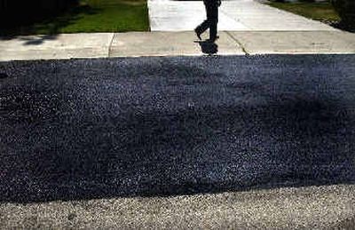 A fresh coat of slurry sealing dries on Fairwood Drive in Spokane on Tuesday afternoon. The process extends the life of cracked, aging pavement.
(Brian Plonka / The Spokesman-Review)