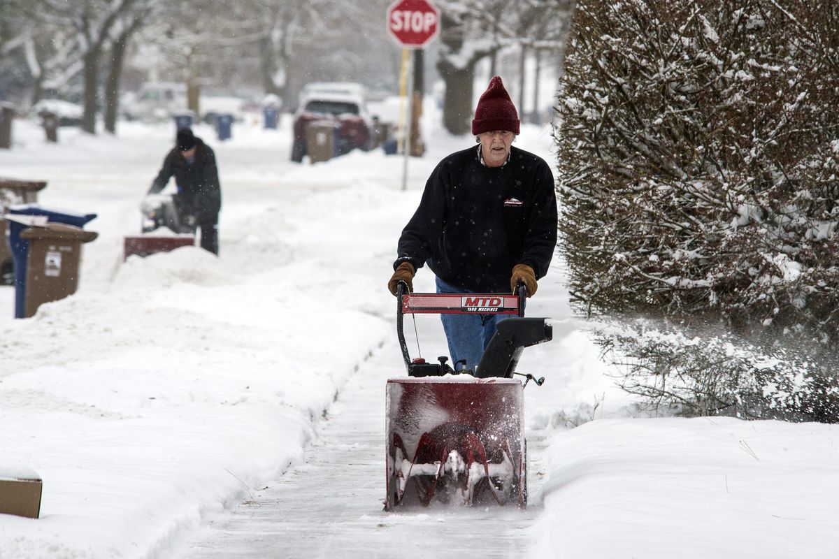 Rick Liptack, right, and Earl Hoal, left, use their snow throwers to clear sidewalks and berms from driveways along 33rd Avenue near Bernard Street, after city snow plows cleared the roads, Friday, Dec. 29, 2017, in Spokane, Wash.  Liptack was removing snow for a neighbor who is in a wheelchair.  (Dan Pelle / The Spokesman-Review)