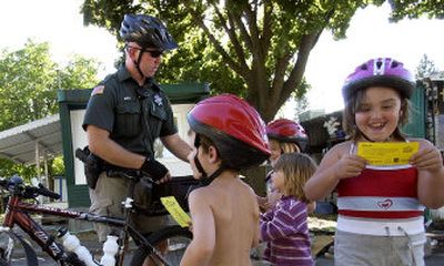 
Deputy Andy Buell passes out free ice cream coupons to kids who have their bike helmets at Rose Haven Mobile Home Park in Spokane Valley on Wednesday during a patrol through the Edgecliff neighborhood. 
 (Liz Kishimoto / The Spokesman-Review)