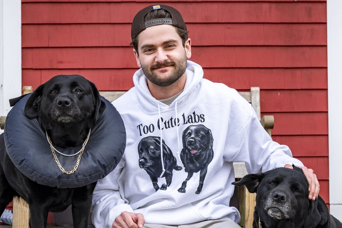 Dawson Gunn with his two black Labrador retrievers, Stink and Bink. He uses some of his earnings from his social account Too Cute Labs to buy them jewelry. 