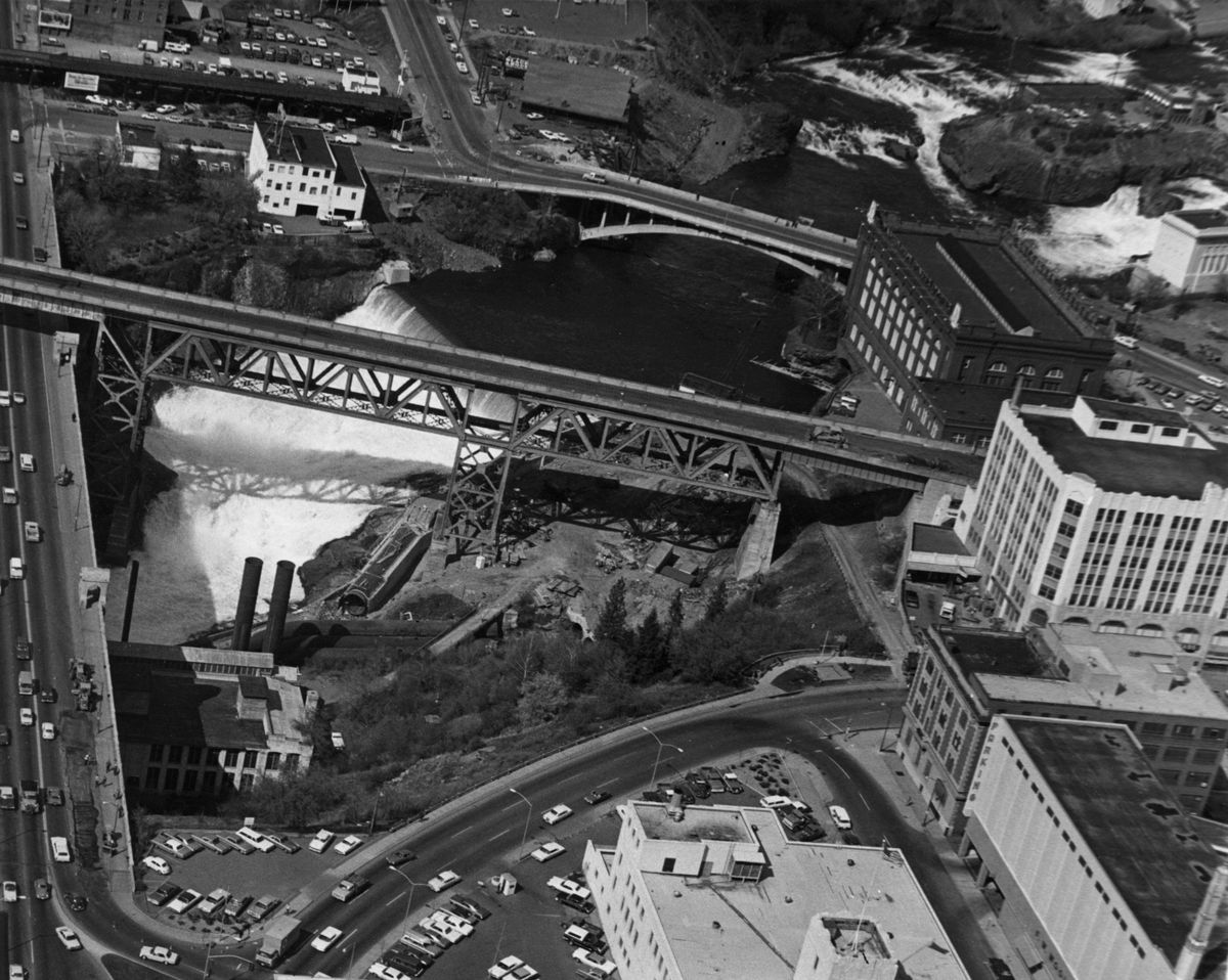 1973: The massive steel Union Pacific railroad bridge, built around 1914, passes above the falls and over the Monroe Street Bridge, left, in this aerial photo. The bridge carried the Union Pacific and Milwaukee Road trains to the Union Depot in downtown Spokane and passed closely to the Montgomery Ward department store at far right, which since the early 1980s has been serving as Spokane City Hall. The bridge was torn down in late 1973 as part of the preparations for Expo ’74, the world’s fair.  (SPOKESMAN-REVIEW PHOTO ARCHIVES)
