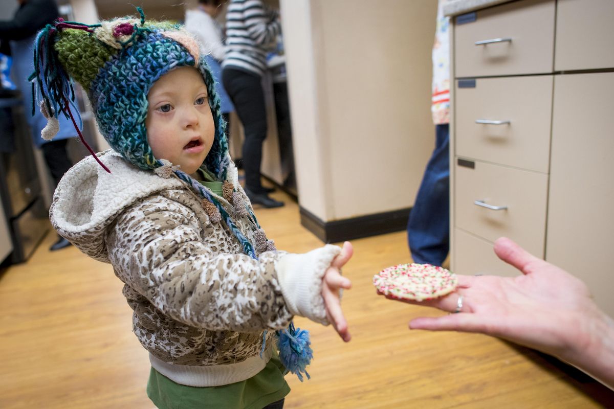 At the Ronald McDonald House, Aryia Harrison, 3, receives a fresh-baked sugar cookie from volunteer Vicki Seely. Each month a group of volunteers comes to the house and bakes upwards of 1200 cookies for the staff and residents. Some of the volunteers have been coming for over 20-years. (Colin Mulvany / The Spokesman-Review)