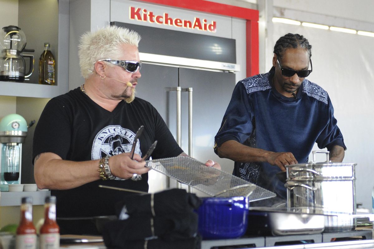 This Feb. 26, 2017, photo made available by WorldRedEye.com, shows rapper Snoop Dog, right, and chef Guy Fieri, cooking together during a demonstration at the South Beach Wine & Food Festival in Miami Beach, Florida. (Ryan Troy / AP)