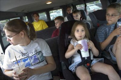 
From left, the Loe children, Erin, Jordan, Ian, Olivia, Natty, Emily and Rory, drink soda and eat Costco hot dogs in their van in the store's parking lot. It has become a tradition for  Barry and Tammy Loe to buy a $1.50 hot dog and soda for dinner for each child who comes shopping. 
 (Holly Pickett / The Spokesman-Review)