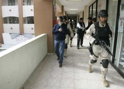 
Associated Press Police chief Jorge Eduardo Montero, who recently escaped an assassination attempt, talks on the phone while being escorted by armed troops during a visit to the mayor's office Monday  in Playas de Rosarito, Mexico.
 (Associated Press / The Spokesman-Review)