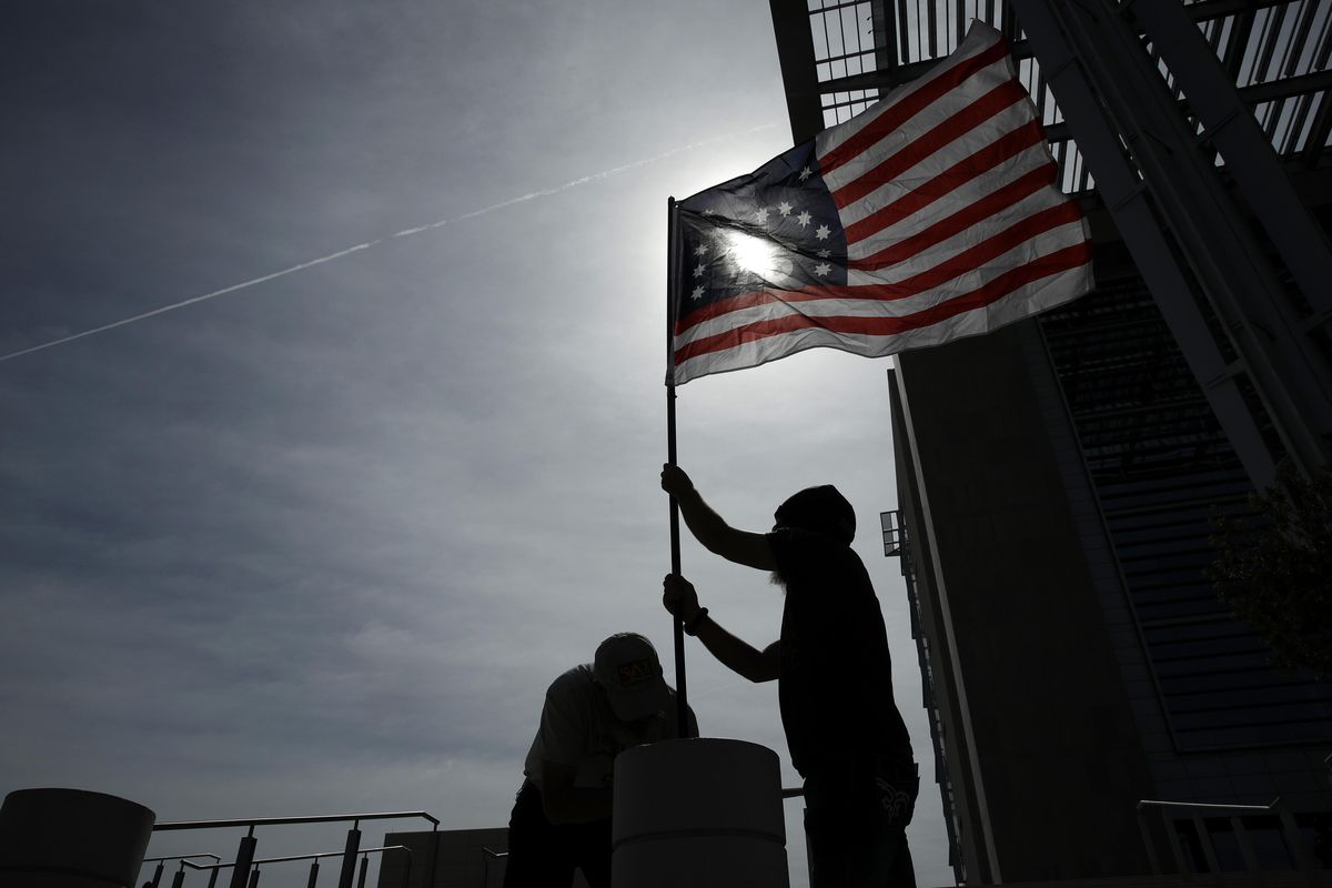 In this April 24, 2017, file photo, supporters raise a flag outside of the federal courthouse in Las Vegas. Federal prosecutors will try again to convince a jury that four men conspired with Nevada rancher Cliven Bundy and his family when they took up arms during a 2014 standoff that stopped federal agents from confiscating cows belonging to the states' rights advocate. July selection begins Monday, July 10. (John Locher / AP)
