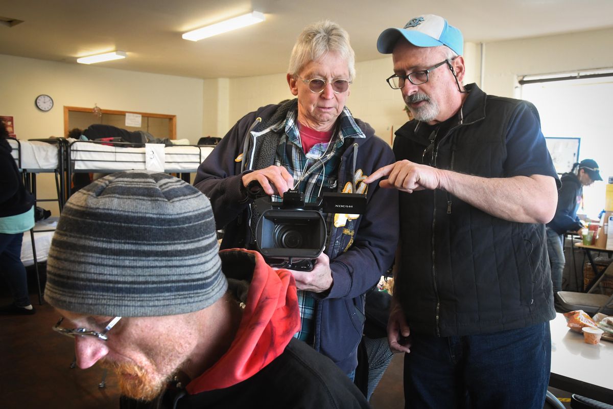 D. W. Clark and Maurice Smith, right, review video Clark shot of Awen Webb, lower left,  Wednesday at the Cannon Street Warming Center. (Dan Pelle / The Spokesman-Review)