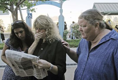 An unidentified train commuter, left, Melinda Moore, center, and Marianne Jones read names of fatalities in the newspaper as they wait at the train station in Chatsworth, Calif. (Associated Press / The Spokesman-Review)