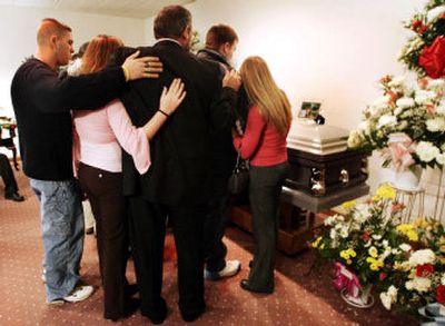 
John Groves, third from left, comforts his children as they gather at the coffin of their uncle Jerry Lee Groves, 56, Saturday in Buckhannon, W.Va. Jerry Lee Groves was one of 12 coal miners killed following an explosion at the Sago Mine.
 (Associated Press / The Spokesman-Review)