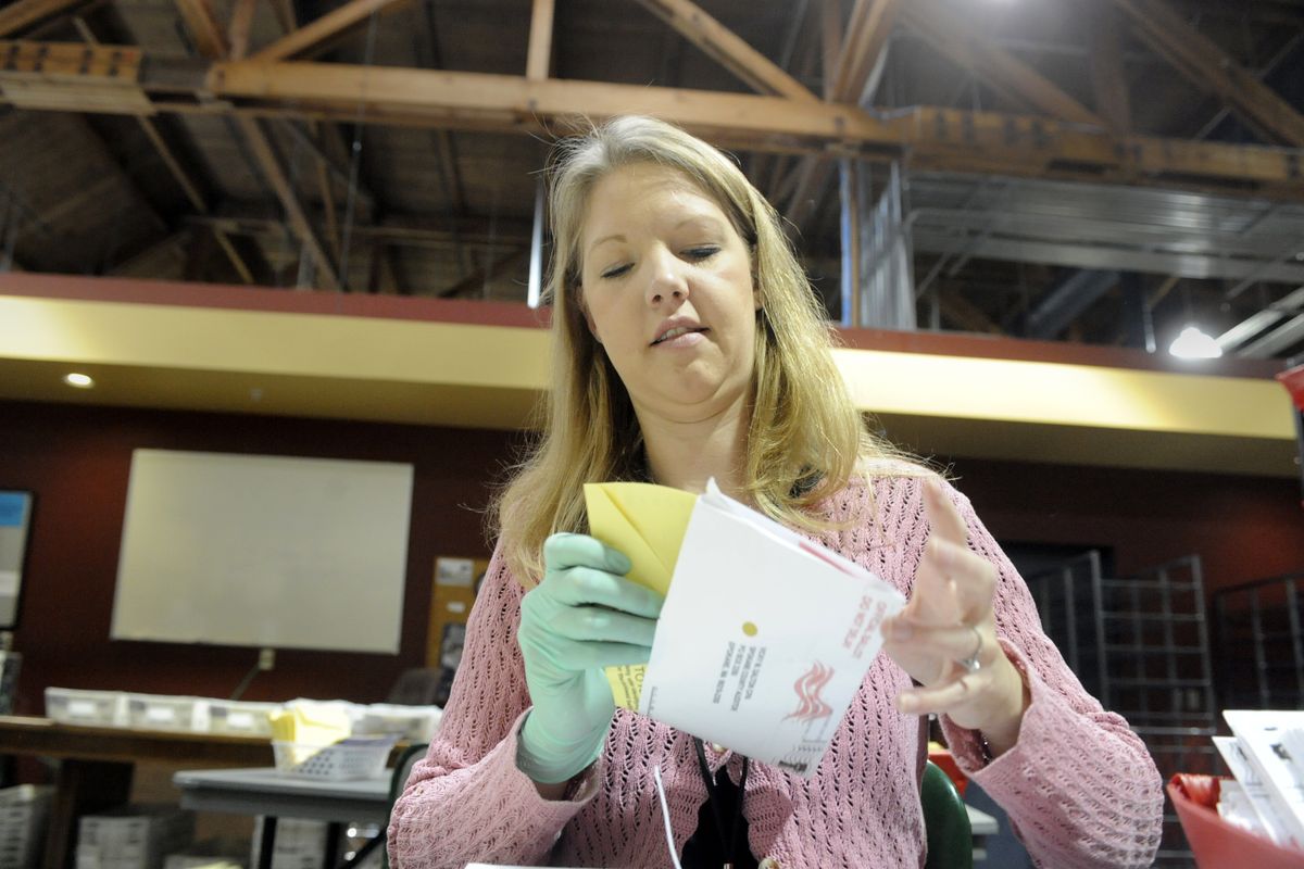 Elections worker Chrystal Shearer separates a ballot, in the yellow envelope, from the mailing envelope, which bears the voter’s name and address, on Monday at the Spokane County Elections Office on Gardner Avenue. Separating the envelopes before counting ensures secrecy. (Jesse Tinsley / The Spokesman-Review)