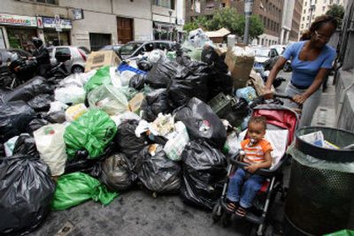 
A woman pushes a stroller past one of several heaps of garbage that has piled up for more than a week in Naples,  Italy, on Monday. 
 (Associated Press / The Spokesman-Review)