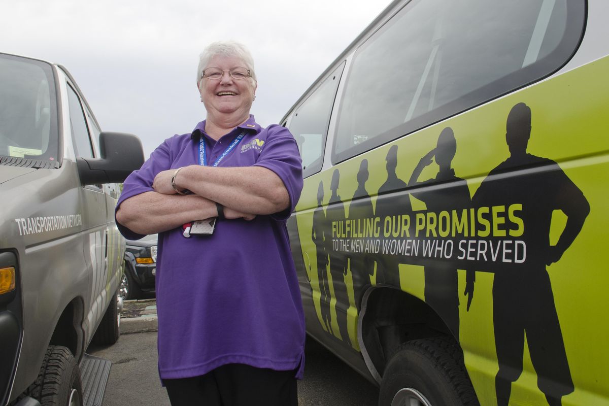 Volunteer transportation coordinator Jeannie Kyle, who’s recently received the national volunteer award from the Disabled American Veterans, stands Aug. 31, 2016, between two of the vans volunteers use to transport patients to and from the Mann-Grandstaff Veterans Administration Medical Center. She has volunteered more than 14,000 hours since starting at the VA in 2004. (Jesse Tinsley / The Spokesman-Review)