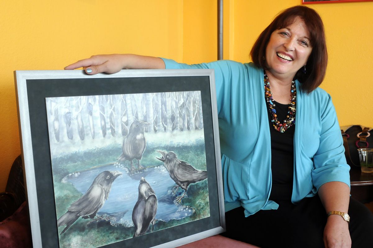 Art teacher Diane Rowen Garmire, of Coeur d’Alene, sits with her 1996 acrylic and ink painting she calls “Things Four Told” Tuesday at Coffee Social in Spokane. (PHOTOS BY JESSE TINSLEY / The Spokesman-Review)