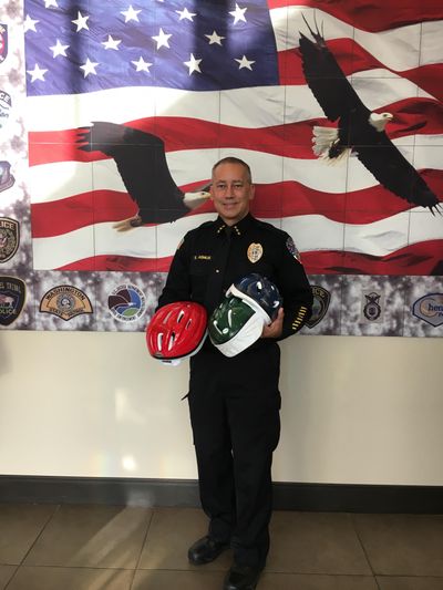 Liberty Lake police Chief Brian Asmus holds several of the children’s bike helmets the department will be distributing throughout the summer. (Liberty Lake Police Department / Courtesy photo)