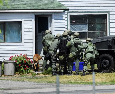 A dog runs out of  a Spokane Valley home after the door was kicked in by SWAT team members Monday afternoon. (J. Bart Rayniak / The Spokesman-Review)