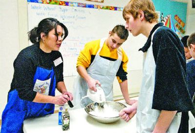Washington State University extension teacher and Food Sense coordinator Kelly Kern helps Ivan Apanasenko, middle, and Alex Abrosimov prepare dough for Valentine's Day cookies in their English language development class at North Pines Middle School in Spokane Valley. 
 (J. BART RAYNIAK / The Spokesman-Review)