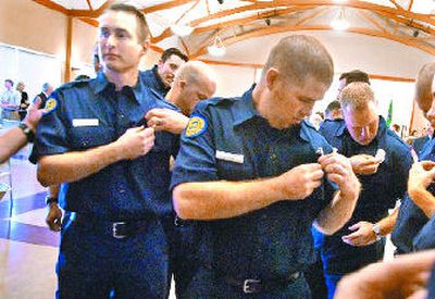 
New Spokane Valley firefighters, left to right front, Paul Turcotte, Shawn Heath, and Kevin Helt check to make sure their new badges have the correct numbers on them after the Fire Academy graduation ceremony Friday at CenterPlace in Spokane Valley. 
 (Holly Pickett / The Spokesman-Review)