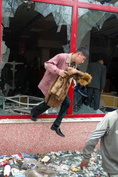 
A man jumps out of a shop window with a fur coat Friday in Bishkek, Kyrgyzstan.
 (Associated Press / The Spokesman-Review)