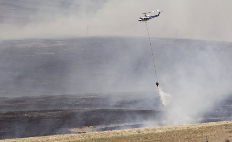 A helicopter dumps water on a wildfire on the L.T. Murray Wildlife area north of Selah, Wash. June 17, 2014.  (Associated Press)