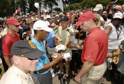
Tiger Woods isn't among leaders, but he is still the people's choice as he signs autographs after finishing his round. 
 (Associated Press / The Spokesman-Review)