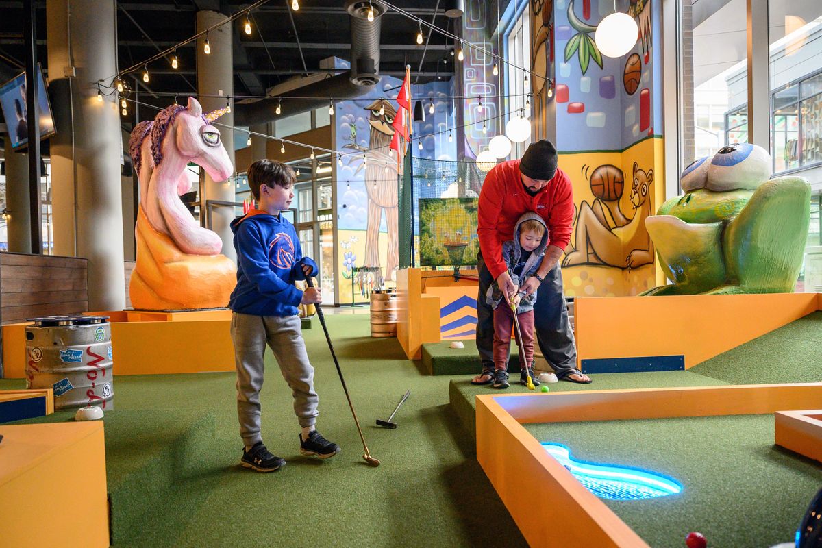 Aaron Oakley plays miniature golf with sons, Hendrix, 7, left, and Brahm, 4, on Monday, Nov. 25, 2019, in the new Flatstick Pub in The M building in downtown Spokane. Seattle-based Flatstick Pub, a casual, craft beer pub with a nine-hole miniature golf course, is open in after several months of construction. (Colin Mulvany / The Spokesman-Review)