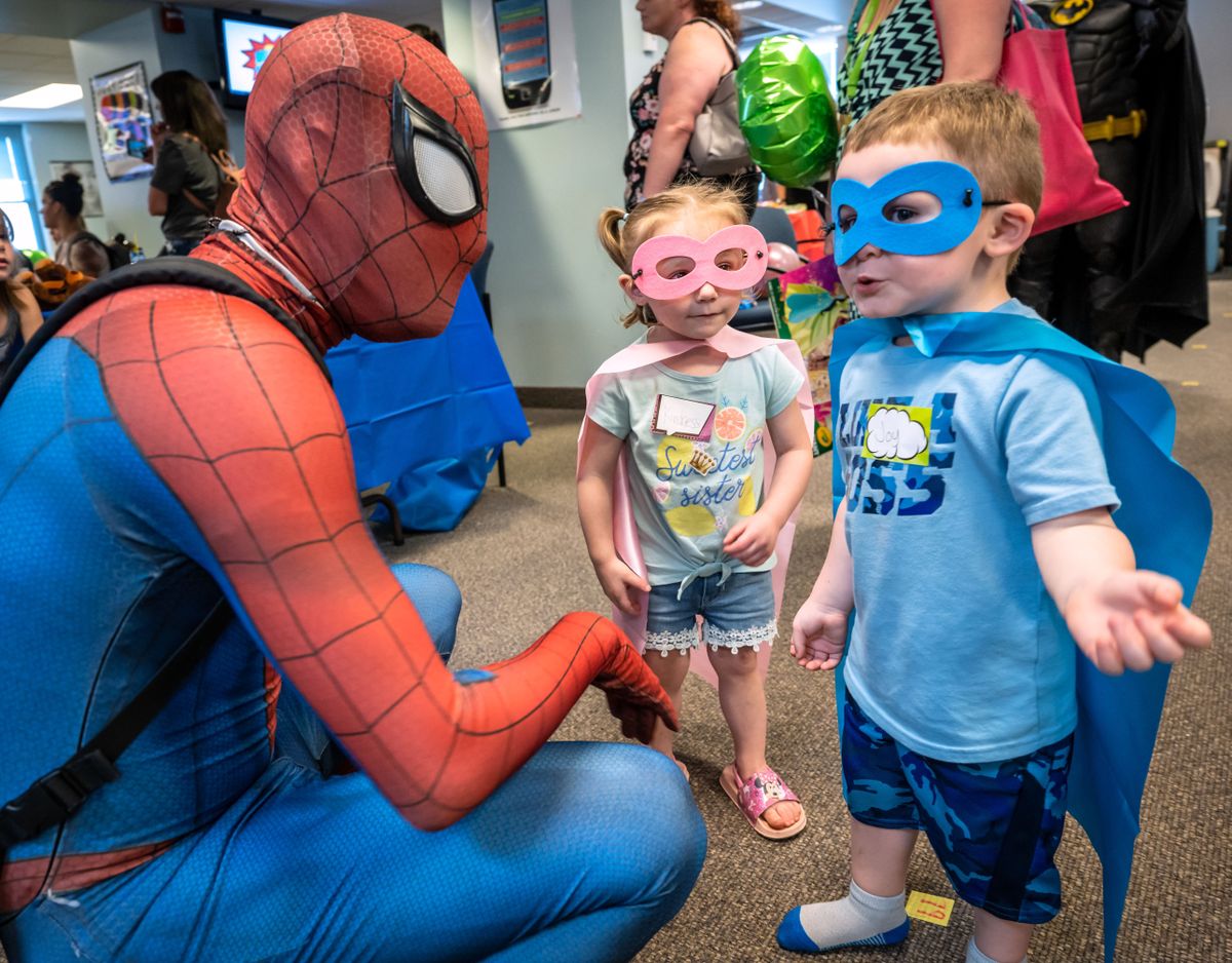 Raelynn Cook, 2, and Jeremiah Stevenson, 3, meet superhero Spider-Man on Friday during Spokane County Superior Court’s celebration of Family Reunification Day in the court’s jury lounge. It’s the first in-person celebration the court and county have been able to hold since the pandemic began, recognizing parents and families who have worked to learn skills, improve understanding and bring their families back together.  (COLIN MULVANY/THE SPOKESMAN-REVIEW)