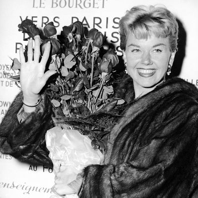 In this April 15, 1955 file photo, American actress and singer Doris Day holds a bouquet of roses at Le Bourget Airport in Paris, France after flying in from London. Day, whose wholesome screen presence stood for a time of innocence in '60s films, has died. She was 97. (AP)