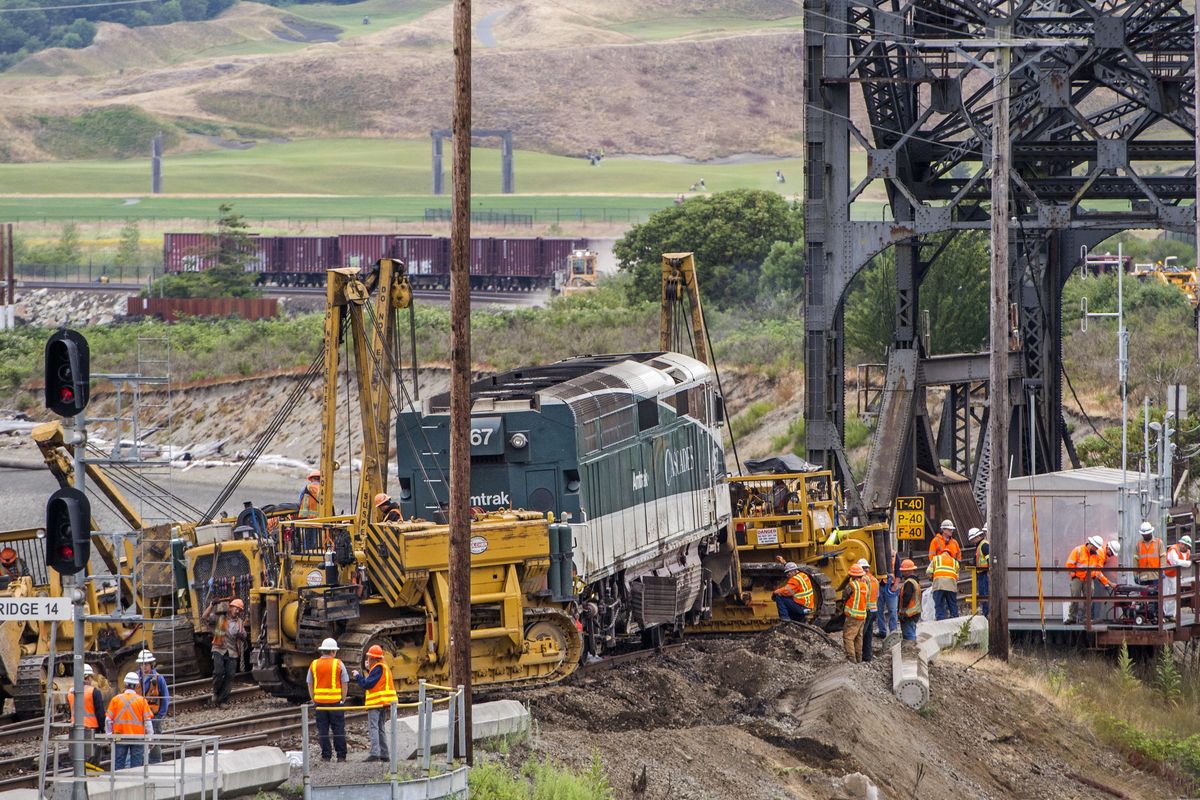 Crews put a derailed Amtrak locomotive back on the tracks Monday, July 3, 2017, in Steilacoom next to the bridge over Chambers Creek, Wash. There were only minor injuries when the locomotive and baggage car of the Amtrak Cascades train carrying 267 passengers derailed on Sunday. (Peter Haley / AP)