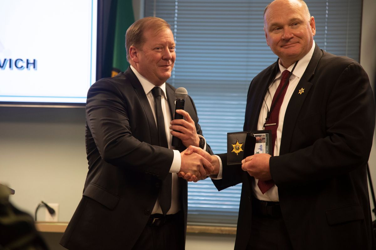 Incoming Spokane County Sheriff John Nowels, left, shakes hands with outgoing Sheriff Ozzie Knezovich with his retired police badge, which will allow him certain special privileges after retirement. The presentation occurred at the Knezovich’s retirement party at the Spokane County office.  (Jesse Tinsley/THE SPOKESMAN-REVI)