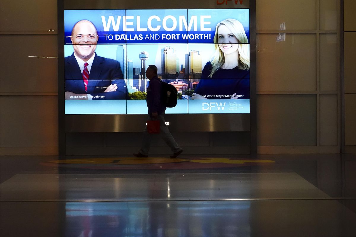 Passengers walk between gates of Terminal A past a display with images of Dallas mayor Eric Johnson and Fort Worth mayor Mattie Parker at DFW Airport on Feb. 3.  (Smiley N. Pool/The Dallas Morning News/TNS)