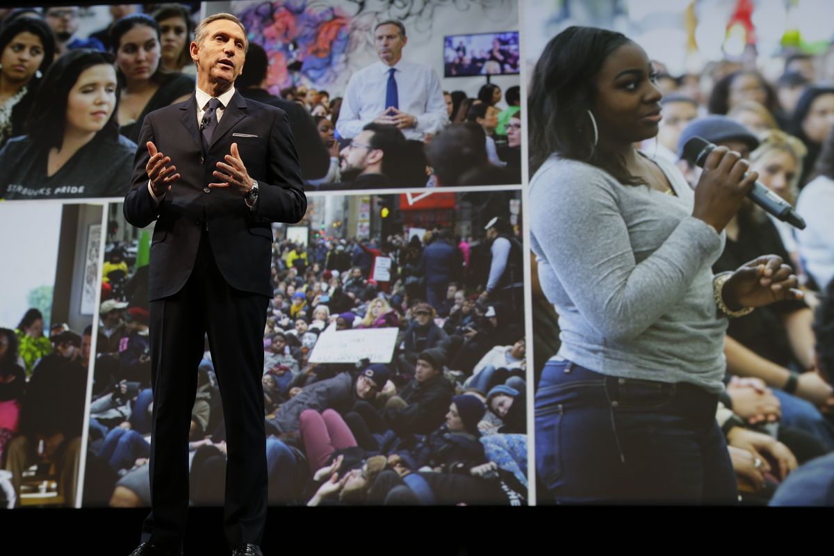 Starbucks CEO Howard Schultz speaks while photos of forums he has held on the topic of race relations across the country are projected behind him on Wednesday at the coffee company’s annual shareholders meeting in Seattle. (Associated Press)