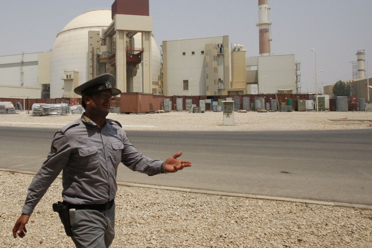 A  security guard directs media at the Bushehr nuclear power plant, with the reactor building  in the background,  outside the southern city of Bushehr, Iran, on Saturday.  (Associated Press)