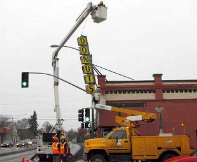 
A city of Spokane Signals and Lighting crew works to remove the Donut Parade sign that blew over in the wind and was lying on the traffic signal at Hamilton and Illinois. The sign was attached to the brick façade of the landmark doughnut shop.
 (Photo courtesy Dave Shaw. / The Spokesman-Review)