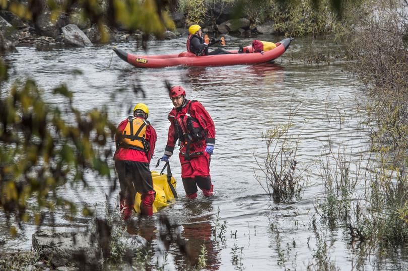 Emergency crews recover a body found floating face down in the Spokane River, near Peaceful Valley, today. (Dan Pelle/SR photo)