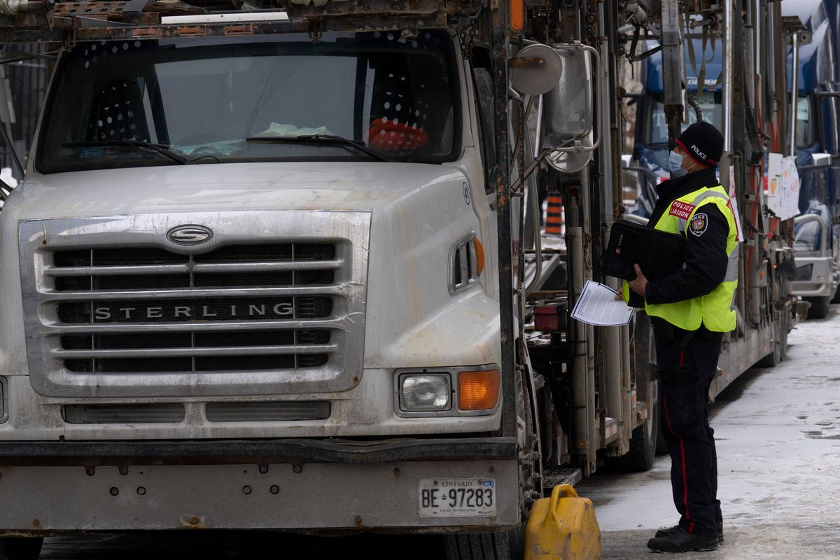 A police officer speaks with a trucker as he distributes a notice to protesters, Wednesday, Feb. 16, 2022 in Ottawa. Ottawa’s police chief was ousted Tuesday amid criticism of his inaction against the trucker protests that have paralyzed Canada