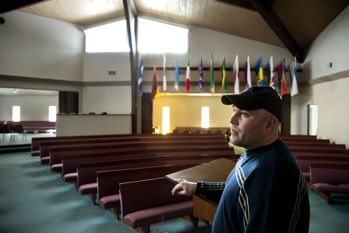 Pastor Nick Hawkins of Lake City Assembly of God in Medical Lake surveys an area of the church on Monday where vandals smashed glass onto pews and tried to throw chairs at the large windows near the ceiling. (Dan Pelle)