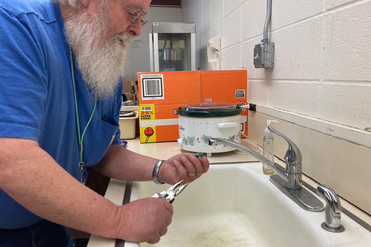 Chris Cornelius, head custodian of Philipsburg Public Schools in Montana, checks a faucet filter in a home economics classroom. Despite a new faucet and inlet pipes, this sink is one of several in the district that continue to show lead levels beyond the state