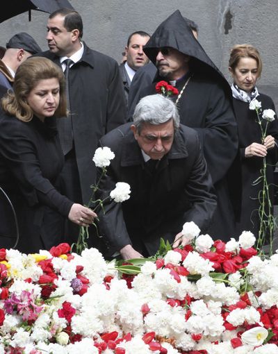 Armenian President Serge Sarkisian, center, and his wife, Rita,  lay flowers at a memorial Saturday to Armenians killed by Ottoman Turks.  (Associated Press)