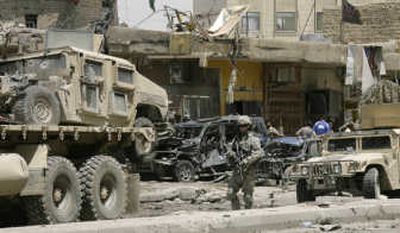
A U.S. soldier secures the area as a damaged U.S. military Humvee is being towed away from a scene of a car bomb attack in central Baghdad, Iraq, on Thursday. Associated Press
 (Associated Press / The Spokesman-Review)