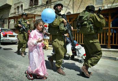 
Israeli soldiers escort an Israeli girl participating in a Purim parade in the West Bank town of Hebron on Sunday. Hebron is a frequent flashpoint of violence. 
 (Associated Press / The Spokesman-Review)
