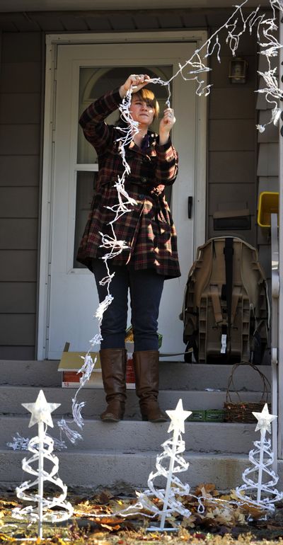 Staking out holiday spirit: Janel Starkey, 31, unwraps her new icicle Christmas decorations for installation on her North Ash Street home on Wednesday. Starkey bought the lights after Christmas last year at a bargain price. She wanted to get the tree lights in the ground before the ground freezes and the job becomes more difficult. (Dan Pelle)