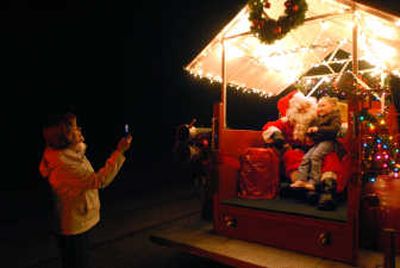 
Sally Kirby takes a photo of her granddaughter Alyssa Conley, 4, with Santa Claus, played by Greg Anderson, on the back of an antique firetruck along a rural road in the Mead area. Spokane County Firefighters plan to continue Santa visits, where Santa greets children, and firefighters collect donations. THE SPOKESMAN-REVIEW
 (JESSE TINSLEY THE SPOKESMAN-REVIEW / The Spokesman-Review)