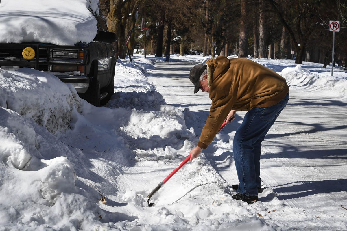 Roy Lee, 69, clears snow and ice from a stormwater drain on Monday, March 4, 2019, outside his home at Shoshone Place and Stevens Street in Spokane. Lee says this winter is a pain.  “Every time I catch up, it snows again.” (Dan Pelle / The Spokesman-Review)
