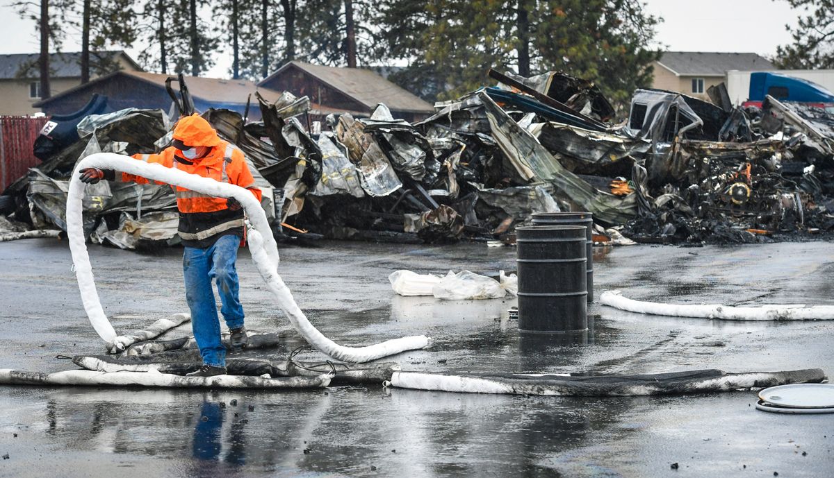 Kipp Silver, of Able Clean-up Technologies, Inc., places booms and pads to soak up and stop motor oil from spreading at the site of a fire at a building holding commercial vehicles, Tuesday morning, Ja. 12, 2021 at Victory Transportation on West Thorpe Road. The blaze broke out Monday evening destroying the structure and melting tote containers holding the oil.  (DAN PELLE/THE SPOKESMAN-REVIEW)