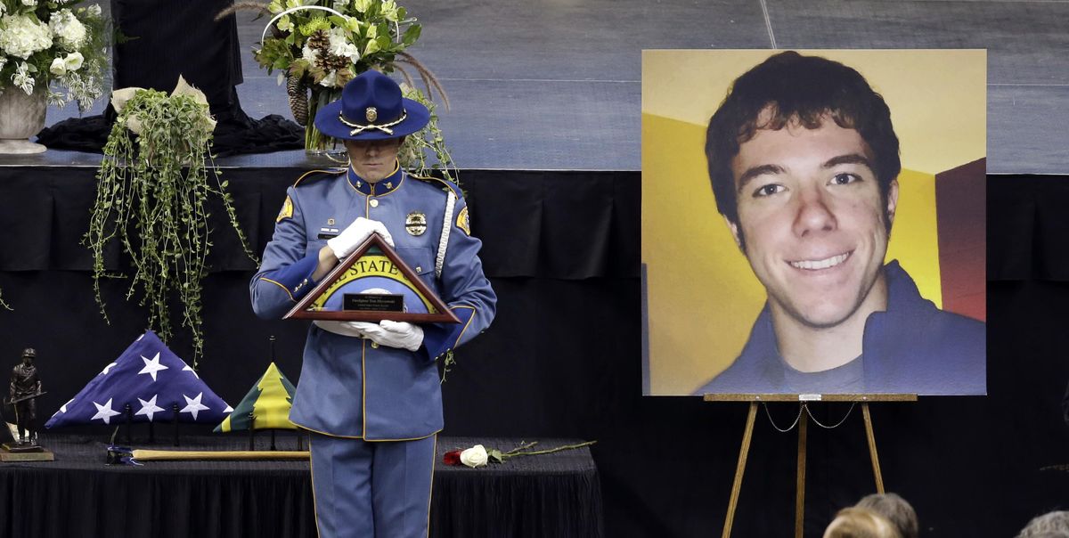 FILE - A Washington State Patrol trooper held a state flag to be presented to the family of Thomas Zbyszewski, pictured in the portrait, who died battling a wildfire near Twisp in 2015. (Elaine Thompson / AP)
