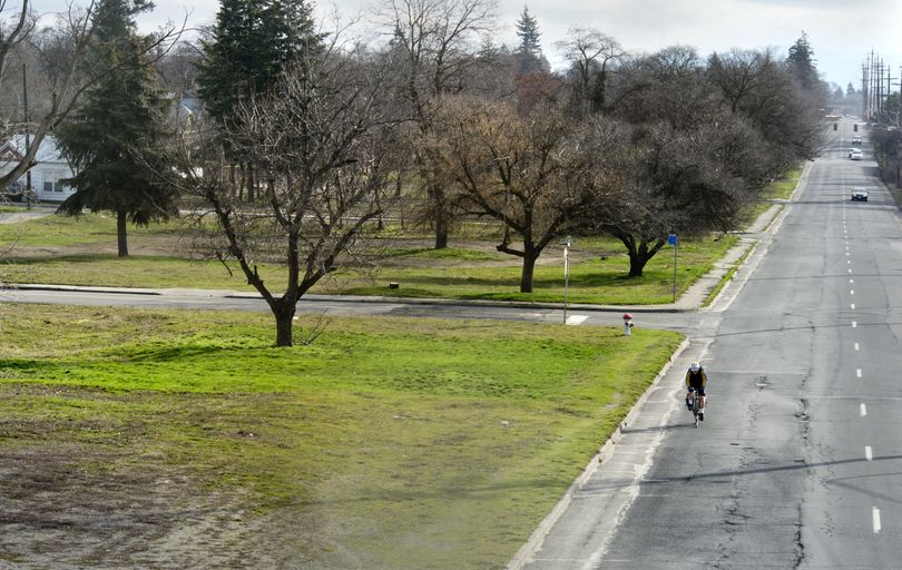A cyclist pedals along Second Avenue at Napa Street past empty lots where homes stood before being removed by the Washington State Department of Transportation. The sites are minimally maintained by the DOT and it could be 15 years before construction will begin for the planned freeway expansion. (Dan Pelle)