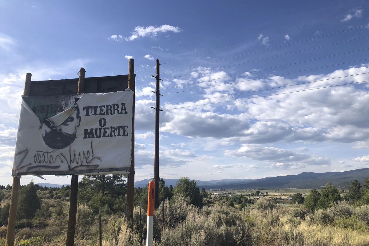 In this June 28, 2020, photo, a sign with Mexican Revolutionary hero Emiliano Zapata demanding "Tierra o Muerte, Zapata Vive" Land or Death, Zapata Lives," sits at the entry of Tierra Amarilla, N.M., the site of the 1967 courthouse raid by armed Mexican American land grant activists. Activists and towns are left wondering what to do with empty spaces that once honored historic figures tied to racism as statues and monuments fall. New Mexico has no formal public art honoring the Tierra Amarilla raid, which helped spark the Chicano Movement.  (Russell Contreras)